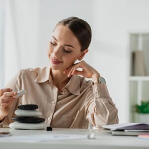 happy businesswoman sitting at workplace with zen stones