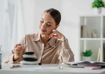 happy businesswoman sitting at workplace with zen stones