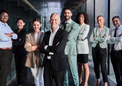 Multicultural business team headed by boss. Posing to camera cheerfully at the office.