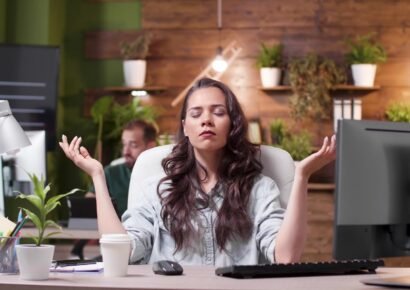 Relaxed zen businesswoman with closed eyes standing in yoga position