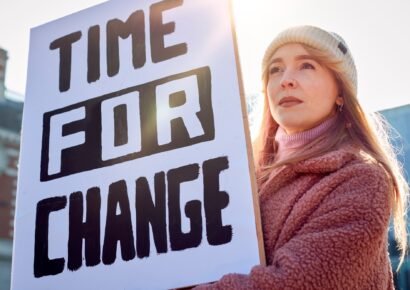 Female Protestor On Demonstration March Holding Time For Change Placard