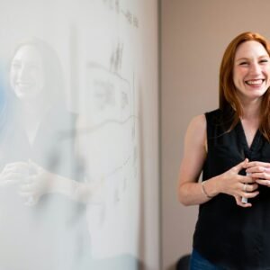 business smiling woman presenting at whiteboard