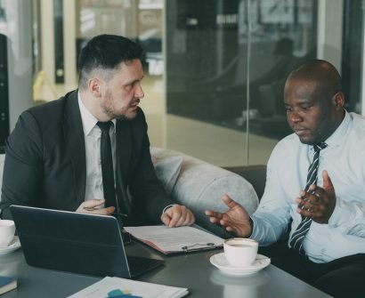 Confrontation Two businessmen discussing documents at a table.